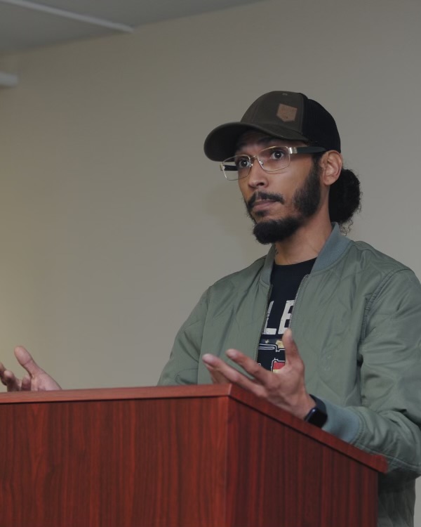 Justin Boswell speaking at a podium to an audience